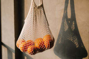 An eco-friendly reusable cotton mesh bag with oranges in it