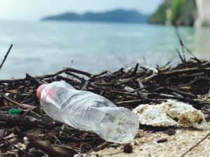 a plastic bottle with microplastics lying next to a river